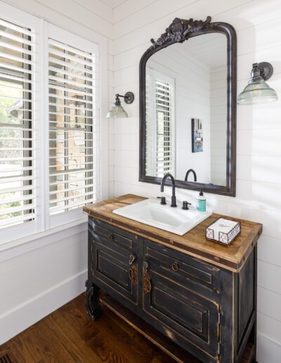 A bathroom with wooden floors and a large mirror.