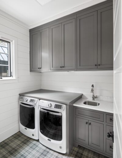 A laundry room with gray cabinets and a washer and dryer.