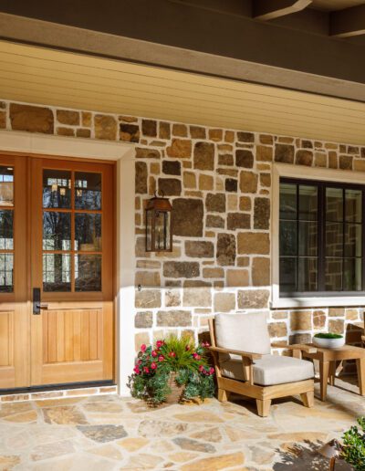 A stone front porch with furniture and a door.